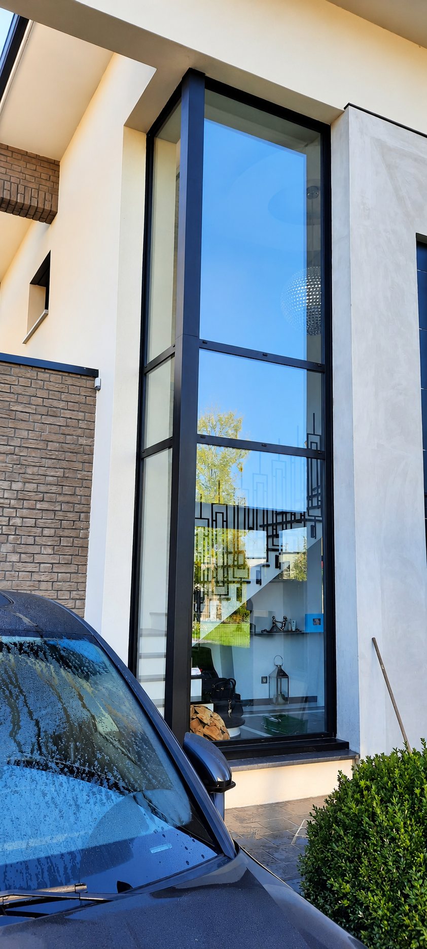 Haute baie vitrée à cadre noir sur une façade claire, vitre propre