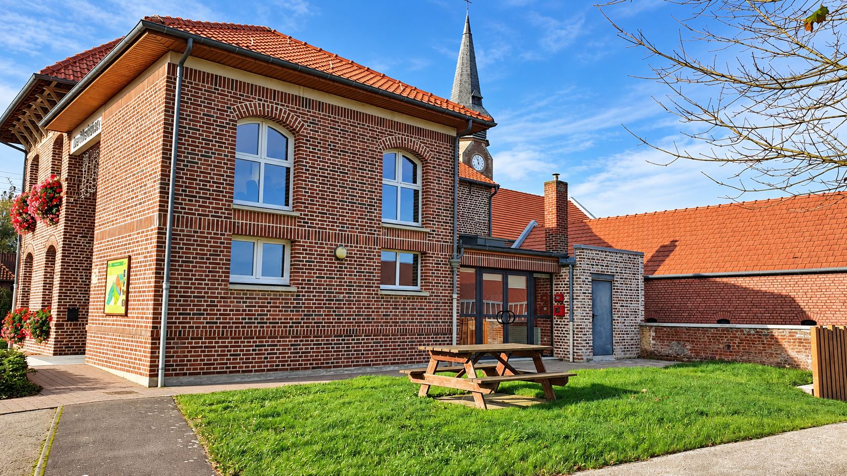 Bâtiment en briques aux hautes fenêtres, clocher en arrière-plan