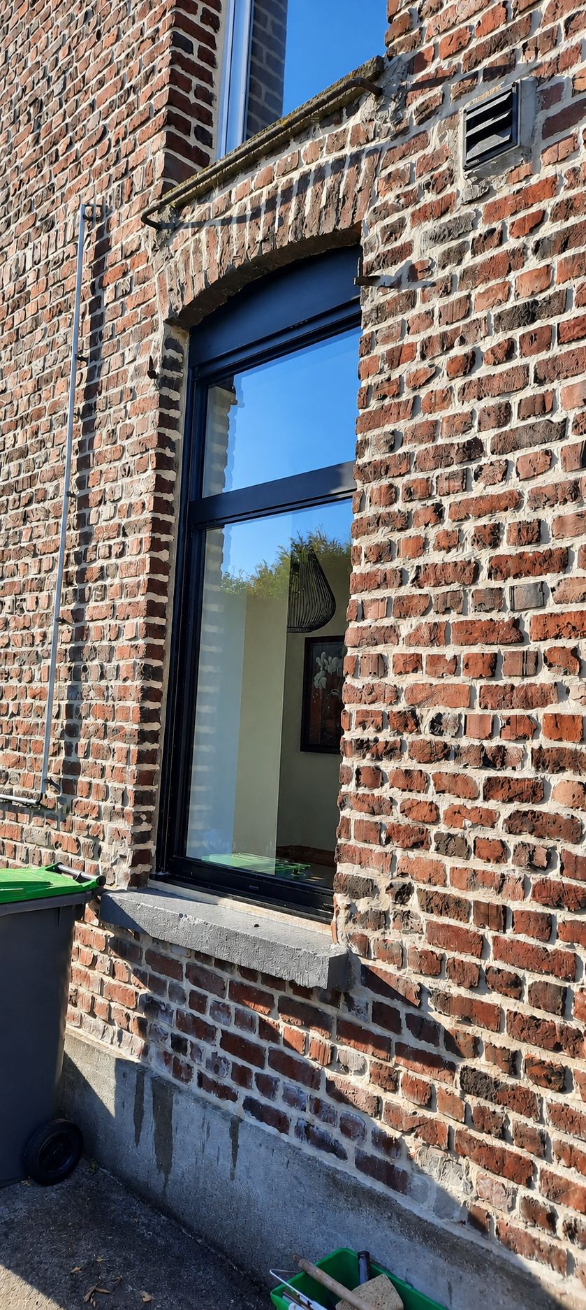 Fenêtre à cadre noir arrondie dans un mur de briques, vitre nette