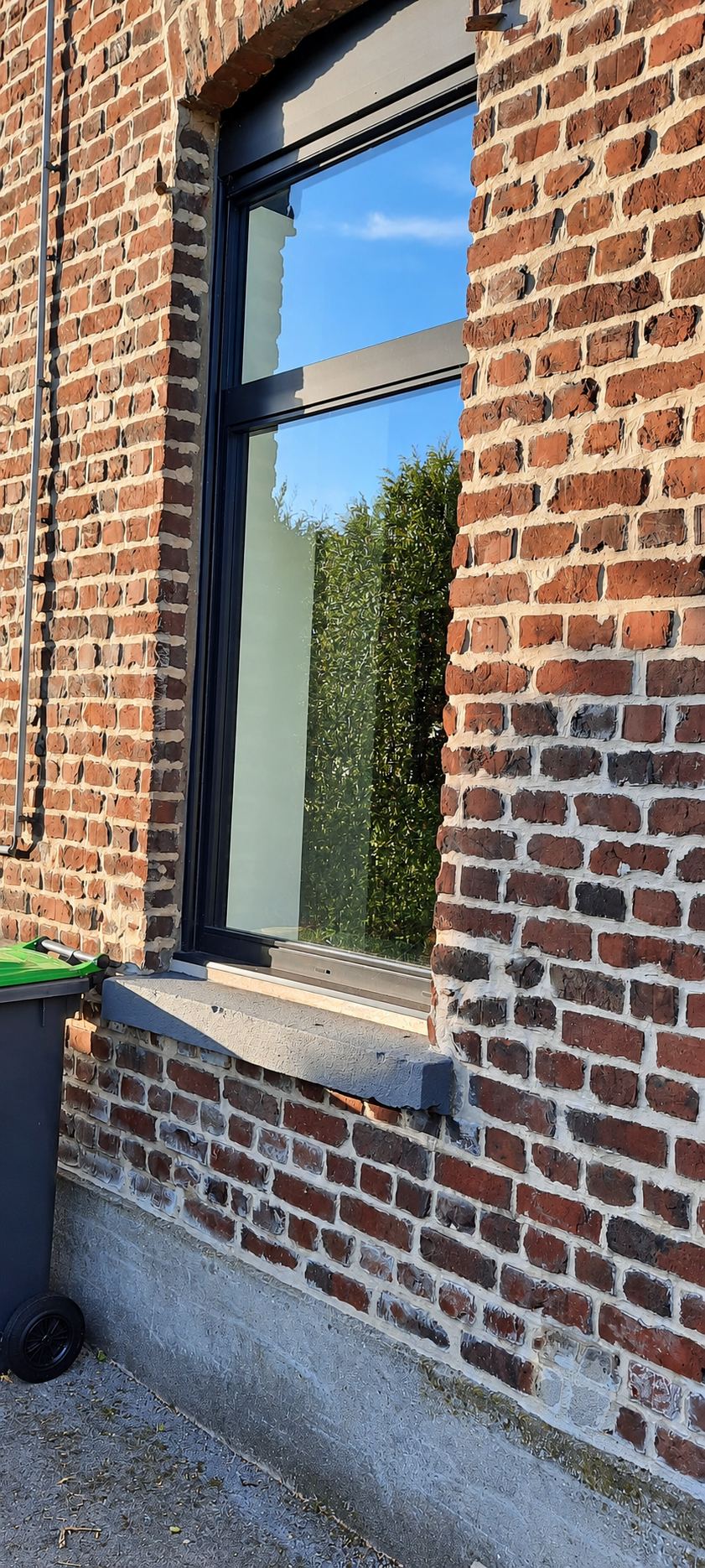 Fenêtre à cadre noir dans un mur de briques, vitre propre