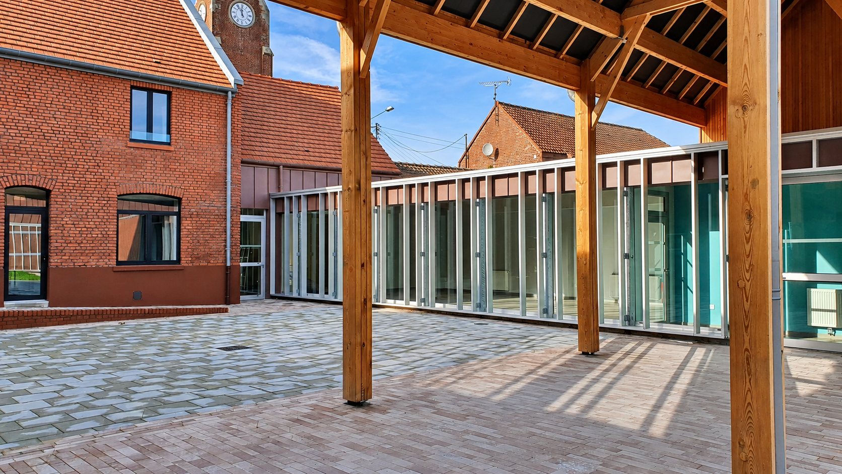 Préau en bois devant une façade entièrement vitrée