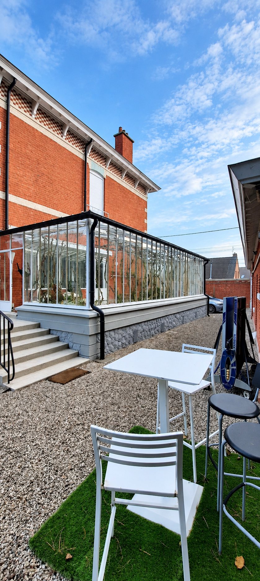 Terrasse vitrée avec garde-corps en verre devant une villa en briques